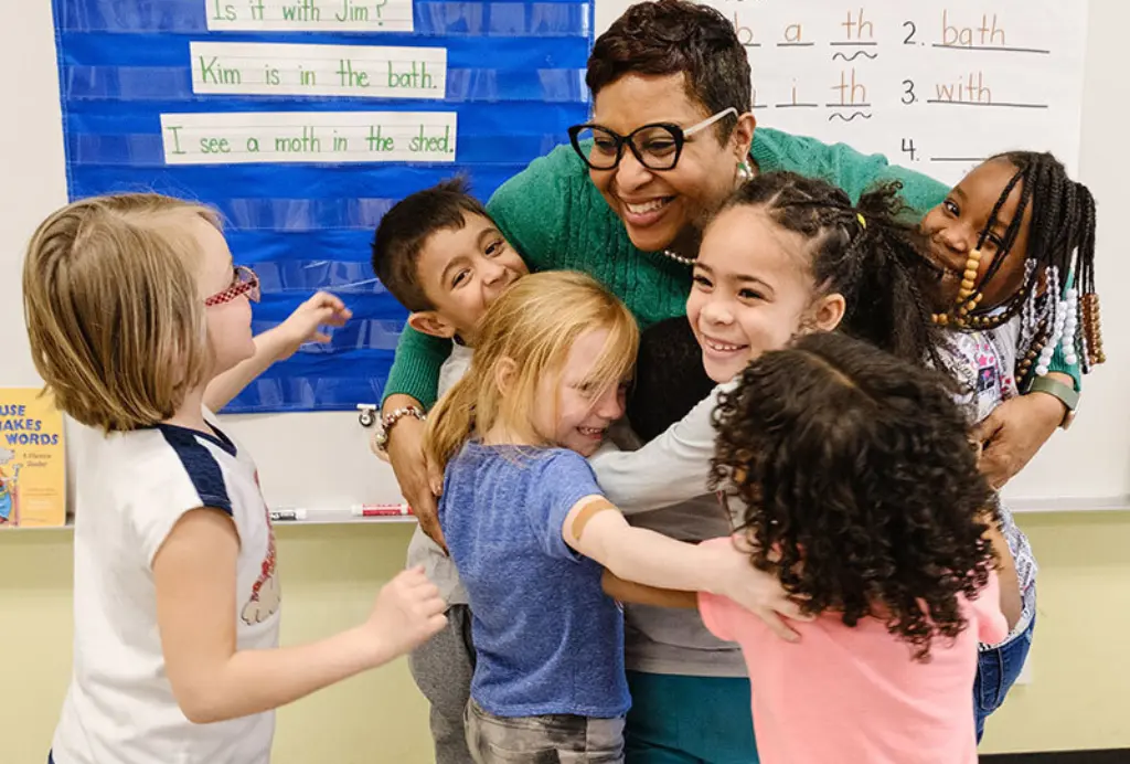 Katina Johnson hugging a group of her students in her classroom.