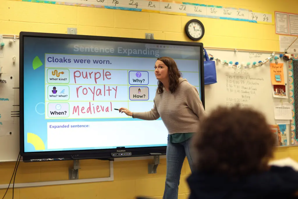 Teacher doing a lesson on sentence expansion on a smartboard.