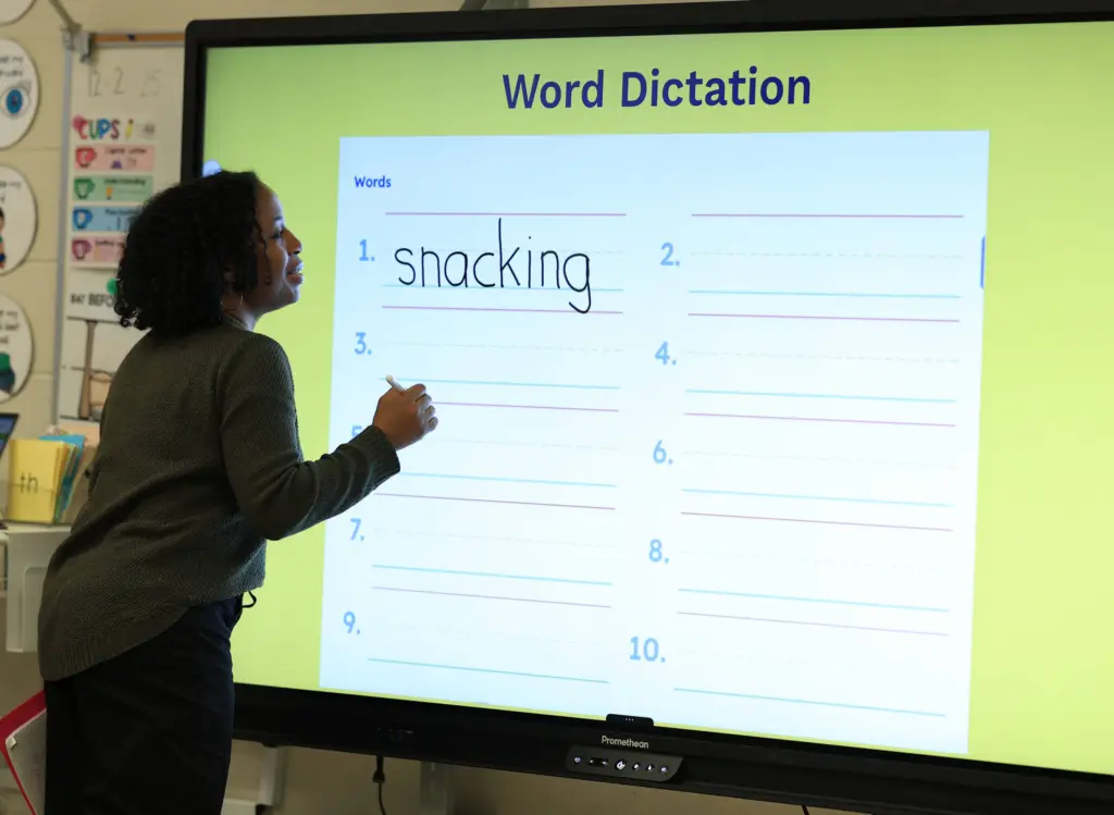 Teacher doing word dictation lesson on smartboard.