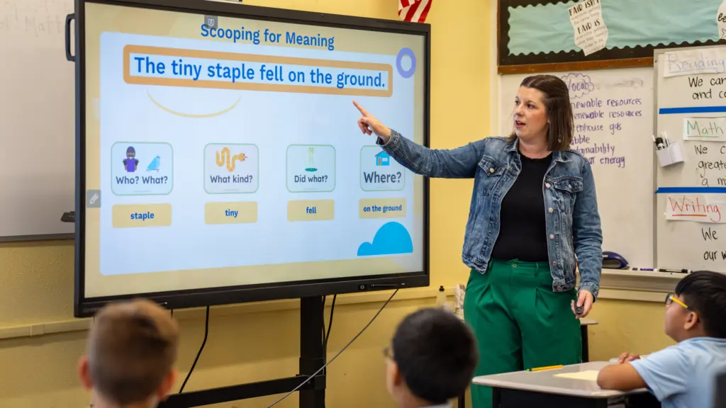 Teacher doing grammar lesson using slides on a smartboard.