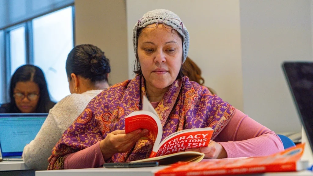 adult reading a book at a table