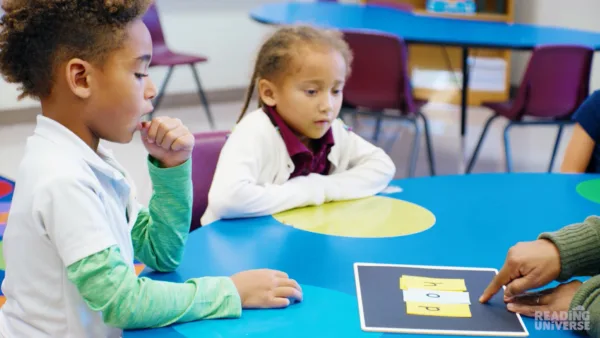 Two students in small group reading words that teacher creates using letter flash cards.
