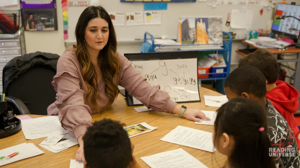 Teacher pointing to students' worksheets in small group.